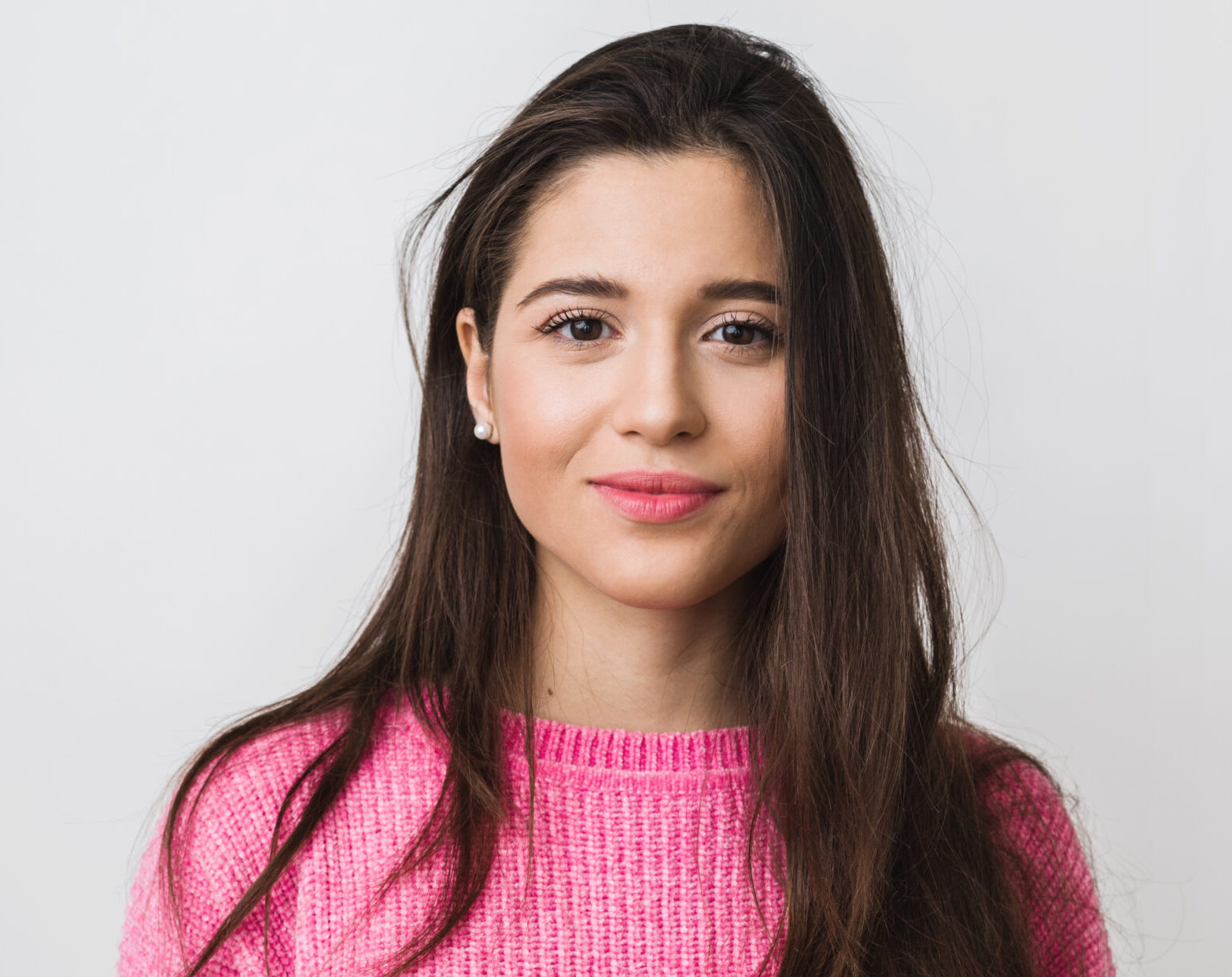 young and beautiful woman in pink warm sweater, natural look, smiling, portrait on white studio background, isolated, long hair